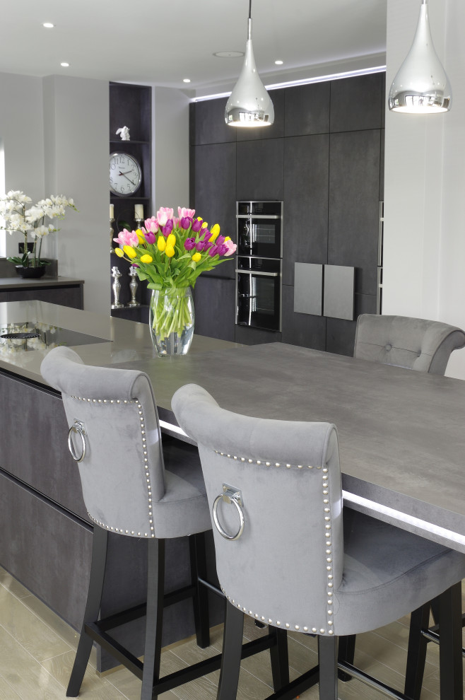 Large contemporary kitchen/diner in Kent with grey cabinets, black appliances, a breakfast bar and grey worktops.