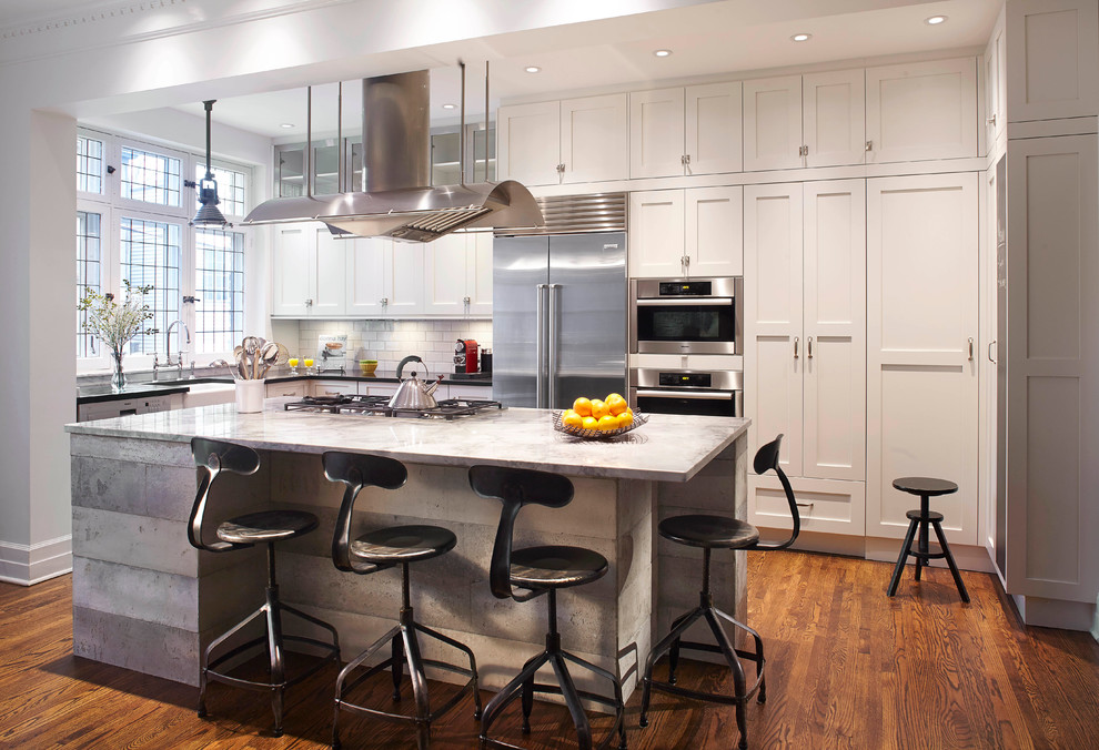 Eat-in kitchen - mid-sized contemporary l-shaped medium tone wood floor eat-in kitchen idea in Montreal with a farmhouse sink, shaker cabinets, white cabinets, granite countertops, white backsplash, subway tile backsplash, stainless steel appliances and an island