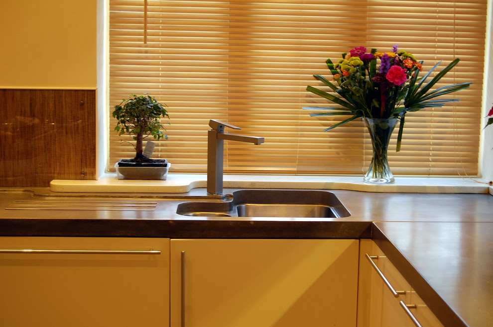 Moderne Küche mit Unterbauwaschbecken, Betonarbeitsplatte und gelben Schränken in London