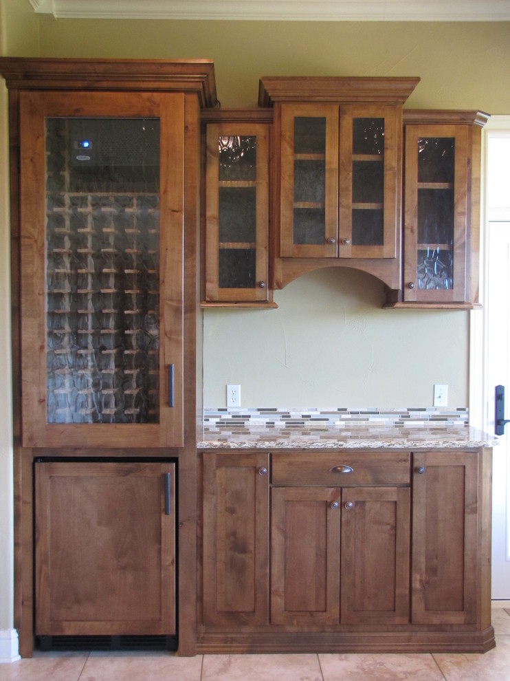 Esempio di una cucina chic di medie dimensioni con ante di vetro, ante in legno scuro, top in granito, paraspruzzi grigio, paraspruzzi con piastrelle di vetro, elettrodomestici da incasso e pavimento in travertino