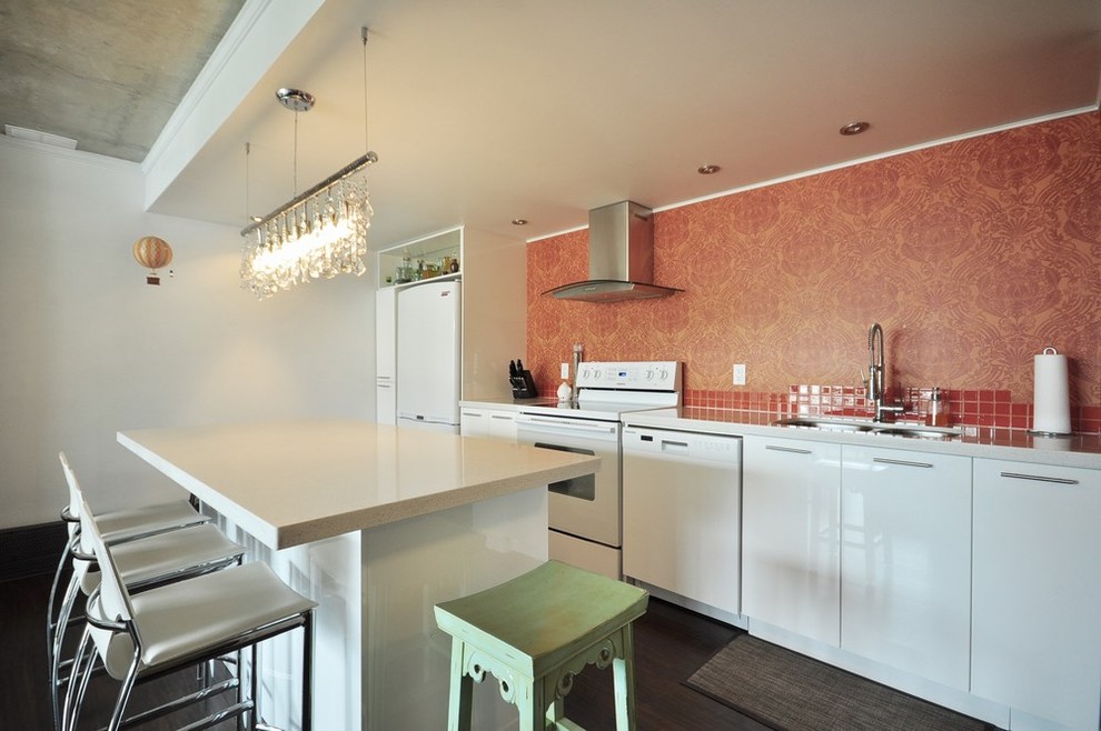Idéer för att renovera ett litet funkis linjärt kök med öppen planlösning, med en undermonterad diskho, släta luckor, vita skåp, granitbänkskiva, orange stänkskydd, stänkskydd i keramik, vita vitvaror, mörkt trägolv och en köksö