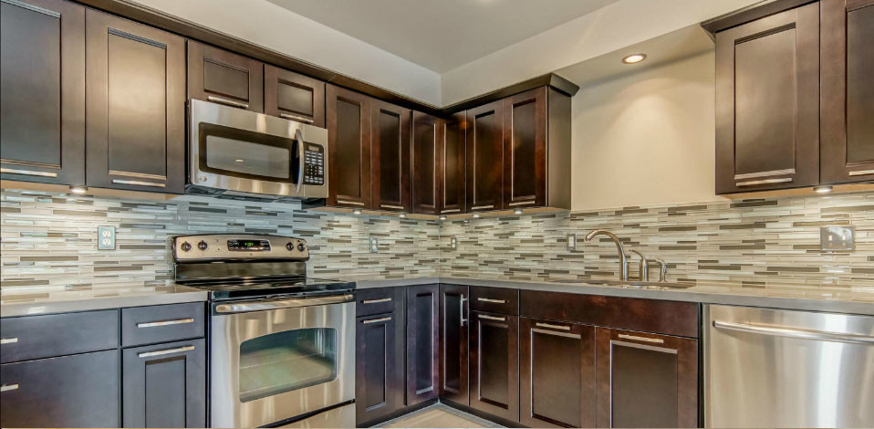 Example of a small trendy u-shaped ceramic tile enclosed kitchen design in Austin with a double-bowl sink, recessed-panel cabinets, dark wood cabinets, glass tile backsplash, stainless steel appliances and no island