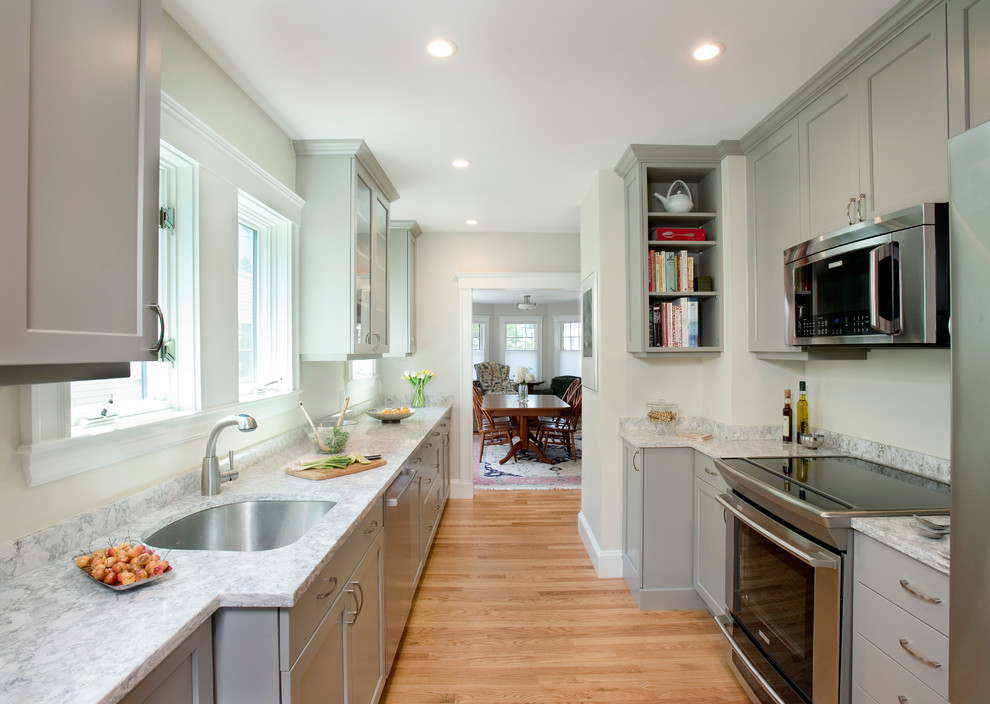 Klassische Schmale Küche mit Unterbauwaschbecken, Schrankfronten mit vertiefter Füllung, grauen Schränken, Küchengeräten aus Edelstahl und hellem Holzboden in Boston