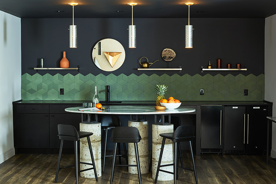 Modern inredning av ett litet svart linjärt svart kök med öppen planlösning, med en undermonterad diskho, luckor med lamellpanel, svarta skåp, bänkskiva i täljsten, grönt stänkskydd, stänkskydd i keramik, rostfria vitvaror, mellanmörkt trägolv, en köksö och brunt golv
