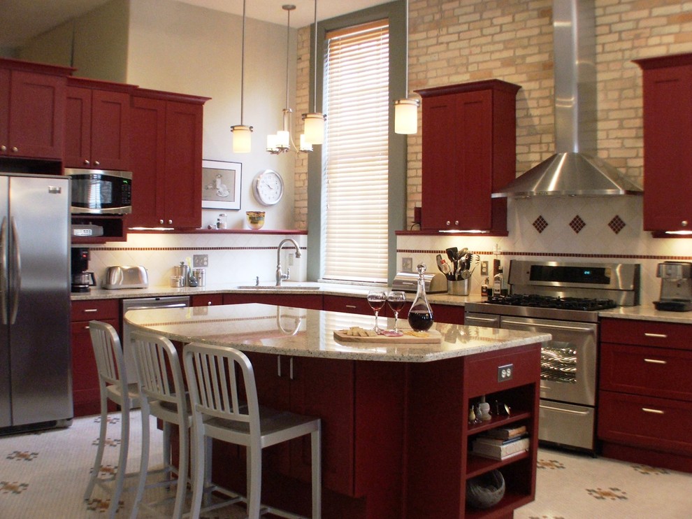 Inspiration for a timeless l-shaped eat-in kitchen remodel in Grand Rapids with an undermount sink, flat-panel cabinets, red cabinets, granite countertops, white backsplash, ceramic backsplash and stainless steel appliances