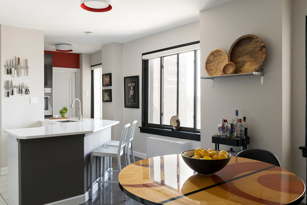 Foto di una cucina minimalista di medie dimensioni con ante lisce, top in superficie solida, lavello da incasso, paraspruzzi bianco, elettrodomestici in acciaio inossidabile, parquet scuro, pavimento nero e ante grigie