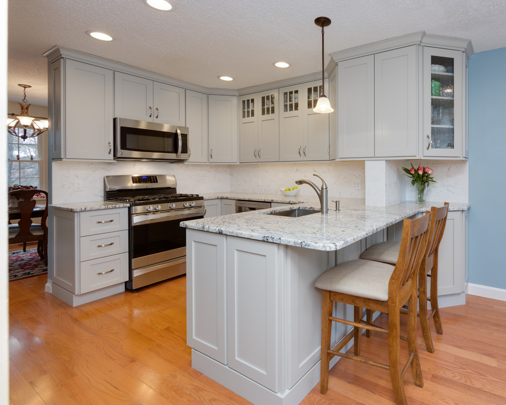 Mid-sized transitional u-shaped medium tone wood floor eat-in kitchen photo in Boston with an undermount sink, shaker cabinets, gray cabinets, granite countertops, stone tile backsplash, stainless steel appliances and a peninsula