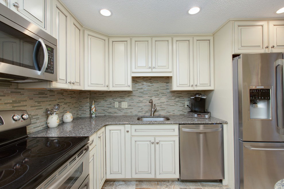 Bild på ett avskilt, mellanstort vintage u-kök, med en undermonterad diskho, luckor med upphöjd panel, vita skåp, bänkskiva i kvarts, flerfärgad stänkskydd, stänkskydd i mosaik, rostfria vitvaror, klinkergolv i porslin och en halv köksö