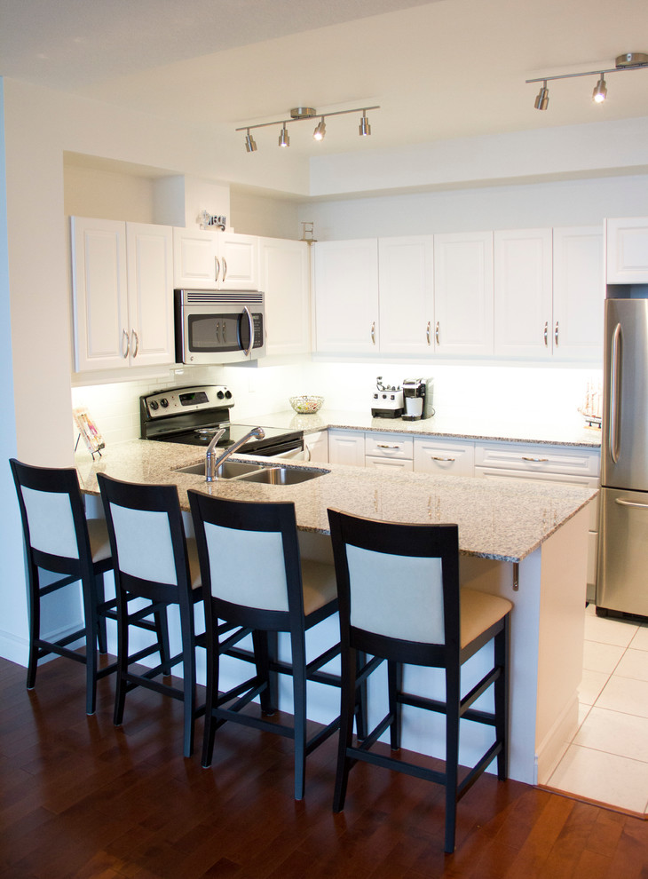 Example of a classic kitchen design in Toronto with white cabinets and granite countertops