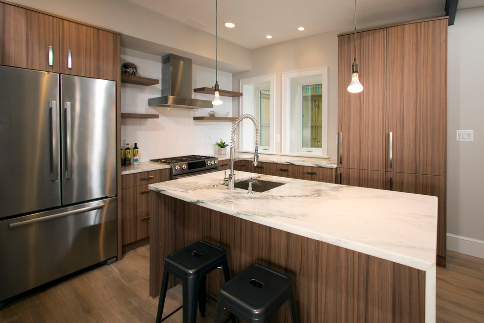 Photo of a medium sized contemporary l-shaped kitchen/diner in DC Metro with a submerged sink, flat-panel cabinets, medium wood cabinets, white splashback, ceramic splashback, stainless steel appliances, an island, marble worktops and medium hardwood flooring.