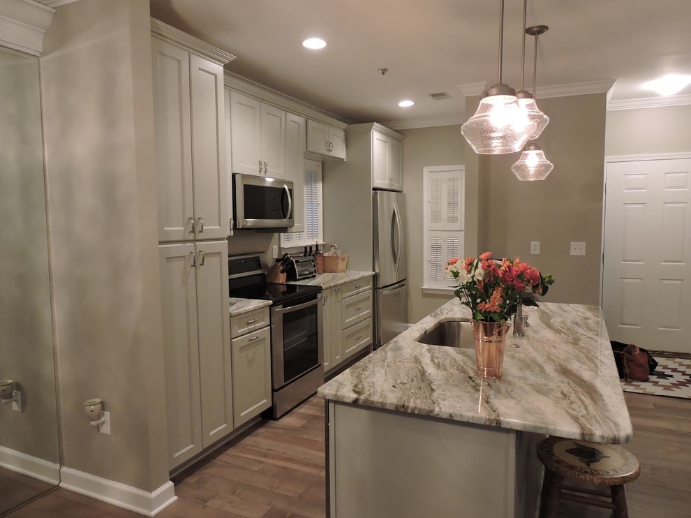 Photo of a small traditional single-wall kitchen/diner in DC Metro with a submerged sink, shaker cabinets, white cabinets, marble worktops, stainless steel appliances, light hardwood flooring, an island and beige floors.