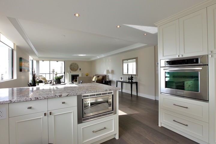 Modern inredning av ett mellanstort kök, med en undermonterad diskho, skåp i shakerstil, vita skåp, granitbänkskiva, grått stänkskydd, stänkskydd i tunnelbanekakel, rostfria vitvaror, mörkt trägolv och en halv köksö