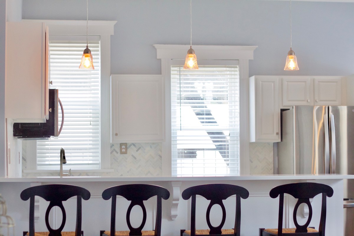 Exempel på ett mellanstort klassiskt kök, med en undermonterad diskho, luckor med upphöjd panel, vita skåp, bänkskiva i kvartsit, vitt stänkskydd, stänkskydd i marmor, rostfria vitvaror, mörkt trägolv, en köksö och brunt golv