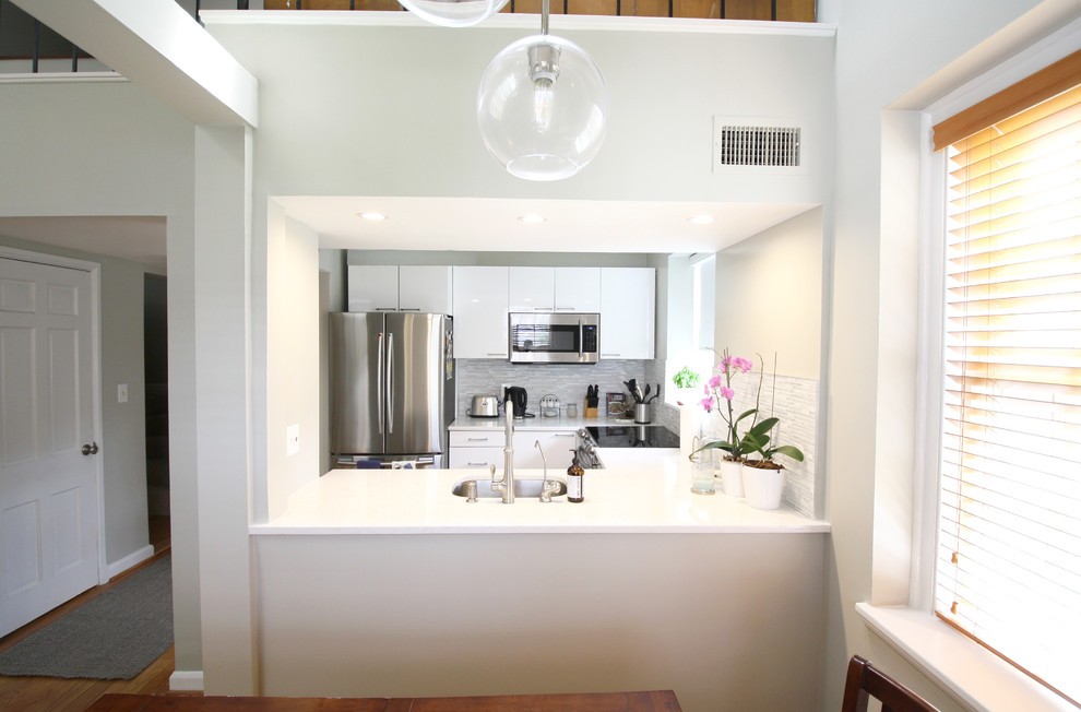 Inspiration för små moderna vitt kök, med en undermonterad diskho, släta luckor, vita skåp, marmorbänkskiva, grått stänkskydd, stänkskydd i glaskakel, rostfria vitvaror, plywoodgolv och en köksö