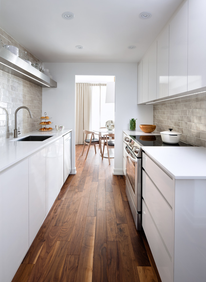 Example of a small trendy galley enclosed kitchen design in Toronto with an undermount sink, flat-panel cabinets, white cabinets, beige backsplash, subway tile backsplash and no island