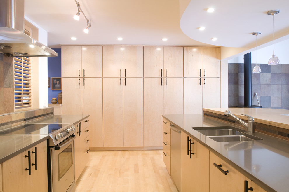 Kitchen - contemporary kitchen idea in Denver with an undermount sink, flat-panel cabinets, light wood cabinets, quartz countertops, stone tile backsplash and stainless steel appliances