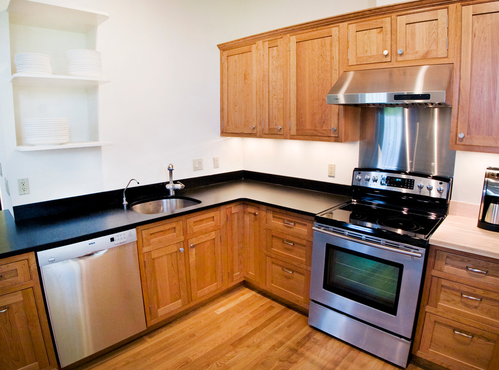 Foto på ett mellanstort funkis l-kök, med en undermonterad diskho, rostfria vitvaror, mellanmörkt trägolv, skåp i shakerstil, skåp i mellenmörkt trä och en halv köksö
