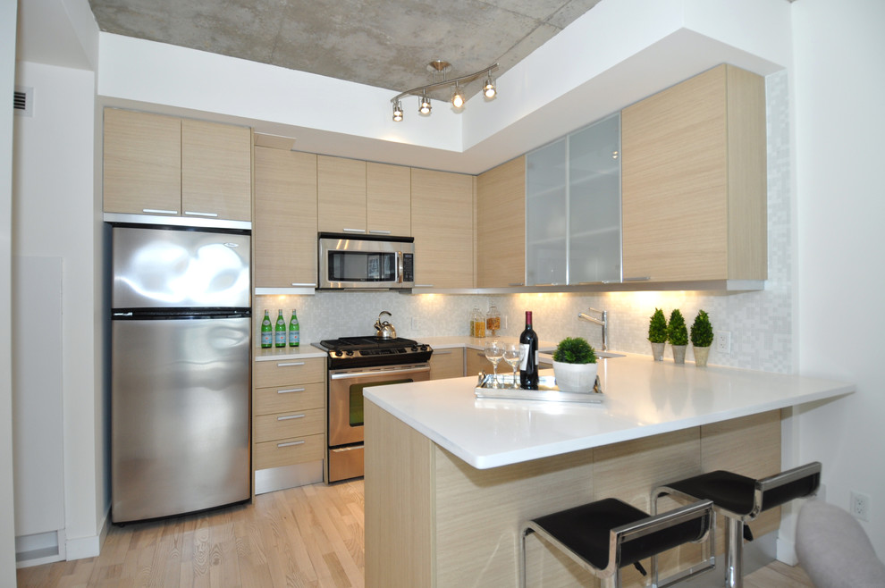 Design ideas for a contemporary u-shaped open plan kitchen in Toronto with a double-bowl sink, flat-panel cabinets, light wood cabinets, grey splashback, stainless steel appliances, light hardwood flooring and a breakfast bar.