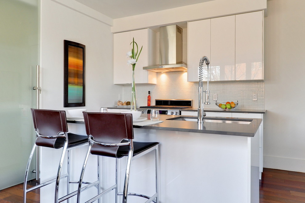 Moderne Küche in grau-weiß mit Unterbauwaschbecken, flächenbündigen Schrankfronten, weißen Schränken, Küchenrückwand in Weiß, Küchengeräten aus Edelstahl und Halbinsel in Montreal