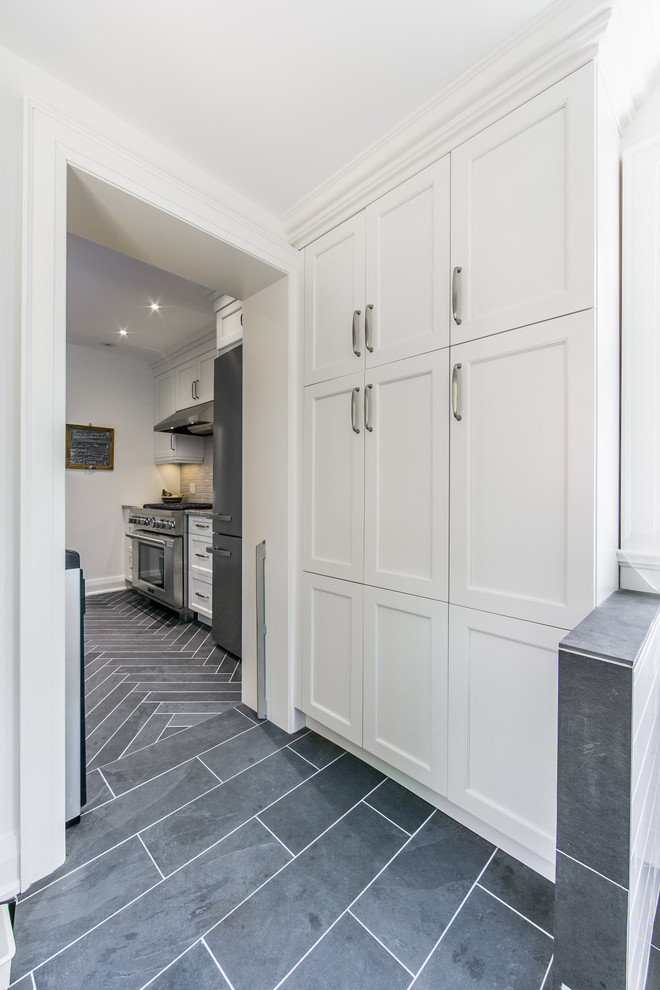 Design ideas for a medium sized traditional galley kitchen pantry in Toronto with shaker cabinets, white cabinets, stainless steel appliances, quartz worktops, a breakfast bar, a submerged sink, grey splashback, ceramic splashback and slate flooring.