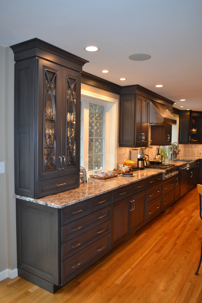 Inspiration for a timeless l-shaped eat-in kitchen remodel in Boston with a farmhouse sink, recessed-panel cabinets, medium tone wood cabinets, granite countertops, gray backsplash, ceramic backsplash and stainless steel appliances