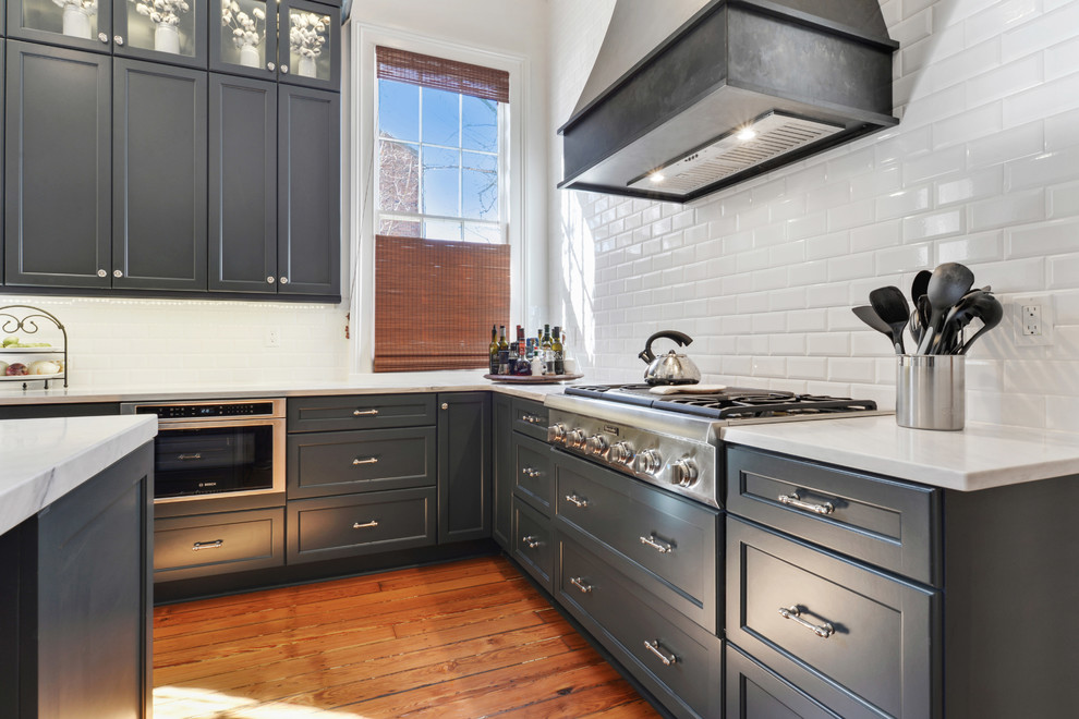 Eat-in kitchen - large transitional light wood floor eat-in kitchen idea in New Orleans with a farmhouse sink, recessed-panel cabinets, blue cabinets, white backsplash, stainless steel appliances and an island