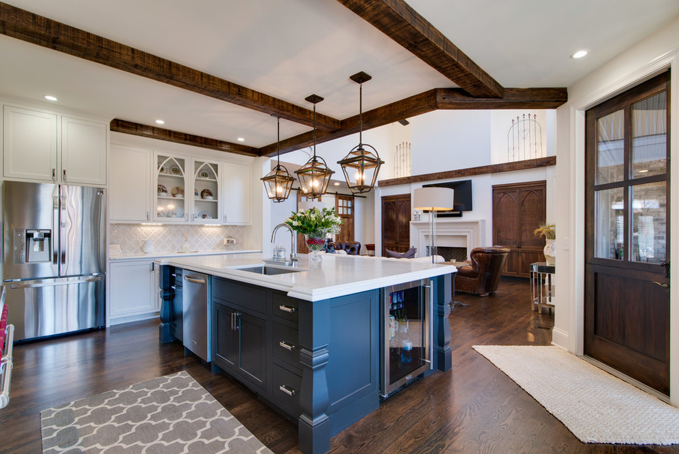 Photo of a large traditional l-shaped open plan kitchen in Nashville with a submerged sink, shaker cabinets, white cabinets, marble worktops, white splashback, ceramic splashback, stainless steel appliances, dark hardwood flooring, an island, brown floors and white worktops.