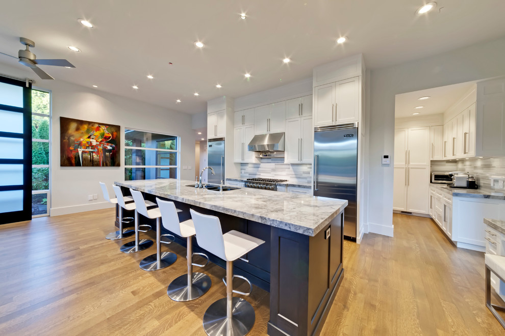 Contemporary single-wall open plan kitchen in Vancouver with a built-in sink, shaker cabinets, white cabinets, granite worktops, grey splashback, stone tiled splashback and stainless steel appliances.