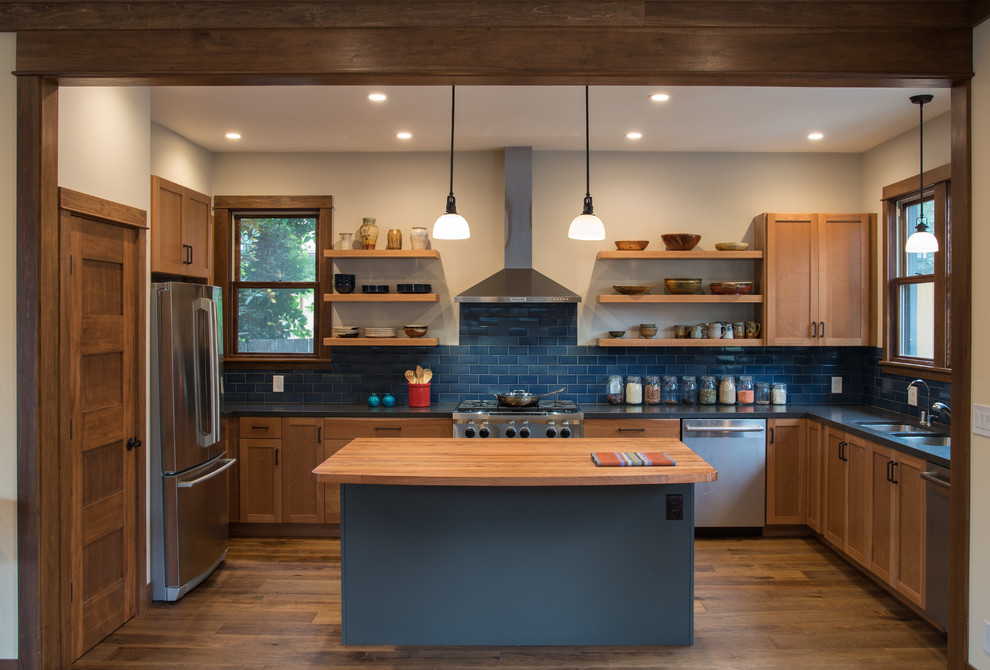 Klassisk inredning av ett grå grått u-kök, med skåp i shakerstil, skåp i mellenmörkt trä, blått stänkskydd, mellanmörkt trägolv, en köksö, en dubbel diskho, stänkskydd i tunnelbanekakel och rostfria vitvaror