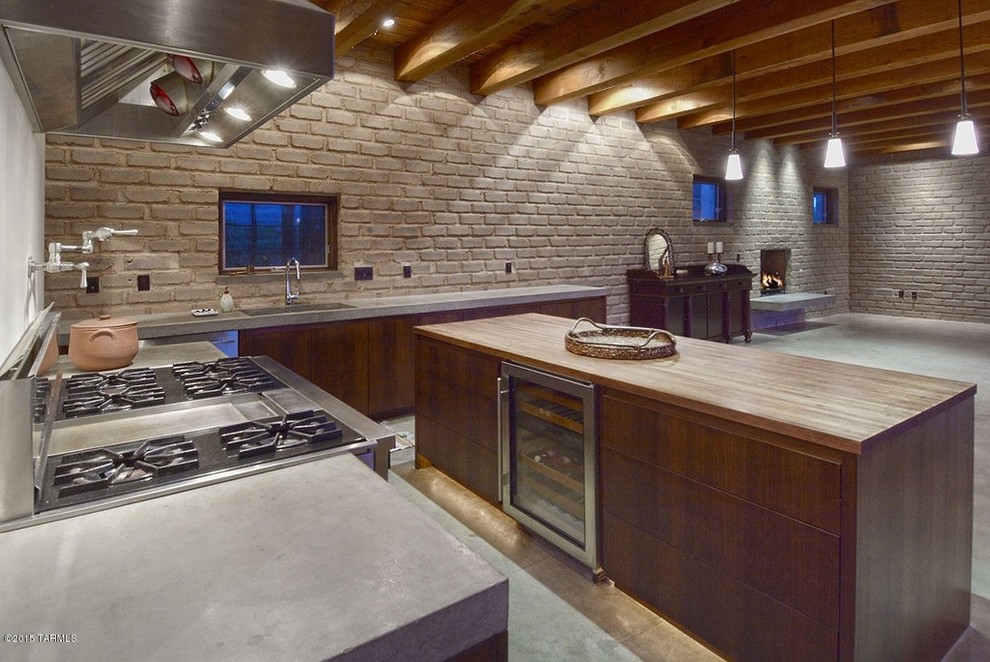 Bild på ett stort funkis linjärt kök med öppen planlösning, med en nedsänkt diskho, släta luckor, skåp i mellenmörkt trä, bänkskiva i betong, rostfria vitvaror, betonggolv och en köksö