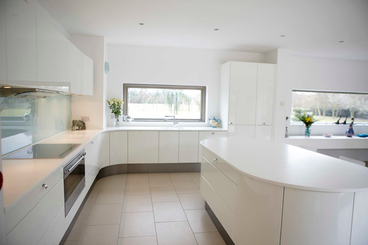 Cette image montre une cuisine encastrable design avec un évier posé, des portes de placard blanches et une crédence en feuille de verre.