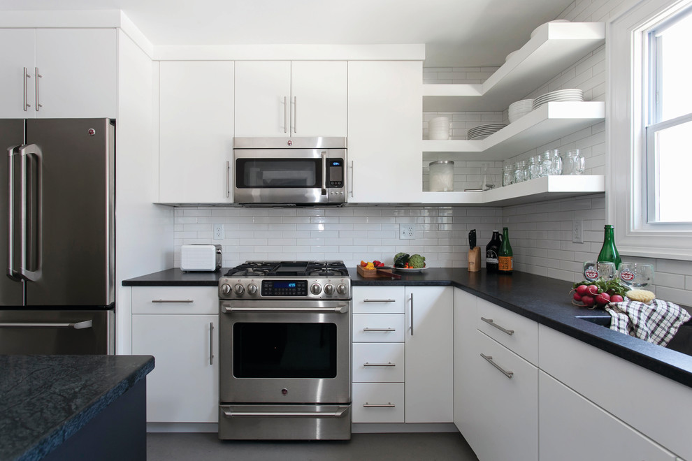 Large contemporary u-shaped kitchen/diner in Raleigh with a submerged sink, flat-panel cabinets, white cabinets, granite worktops, white splashback, ceramic splashback, stainless steel appliances, concrete flooring, an island and grey floors.