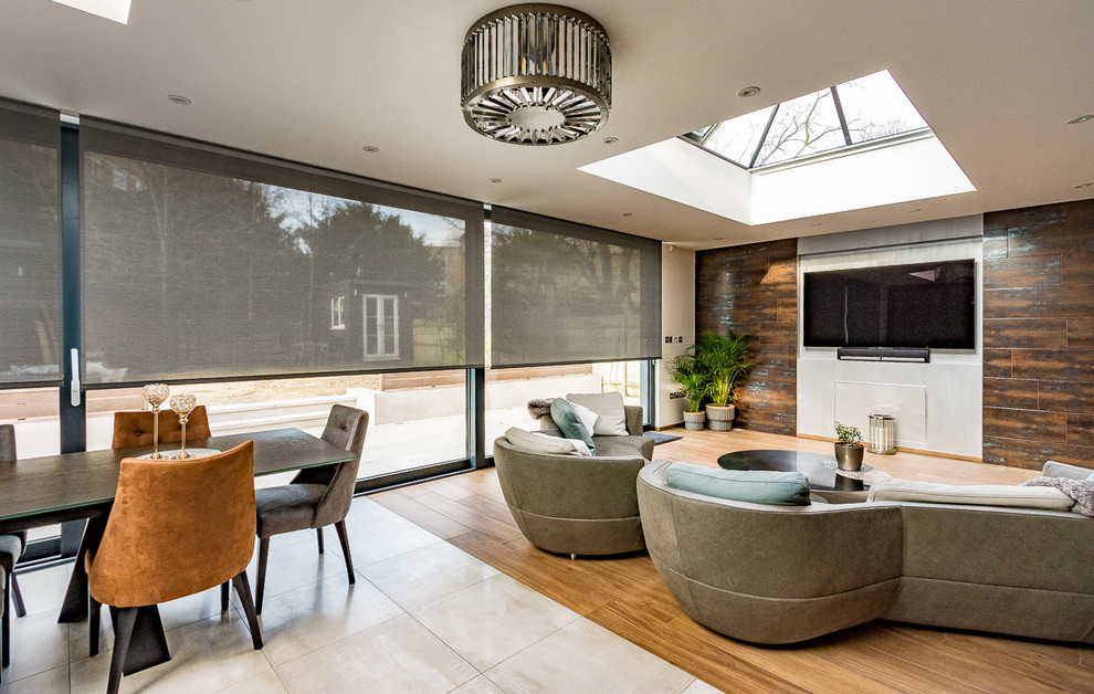 This is an example of a large modern l-shaped open plan kitchen in Surrey with an integrated sink, flat-panel cabinets, grey cabinets, composite countertops, white splashback, slate splashback, stainless steel appliances, porcelain flooring, an island and grey floors.
