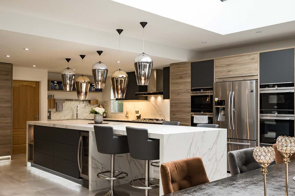 Inspiration for a large modern l-shaped porcelain tile and gray floor open concept kitchen remodel in Surrey with an integrated sink, flat-panel cabinets, gray cabinets, solid surface countertops, white backsplash, slate backsplash, stainless steel appliances and an island
