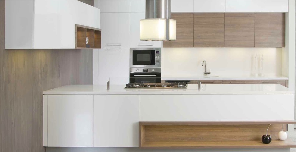 Exemple d'une cuisine ouverte parallèle tendance en bois brun de taille moyenne avec un placard à porte plane, un plan de travail en surface solide, une crédence beige, un électroménager en acier inoxydable et îlot.