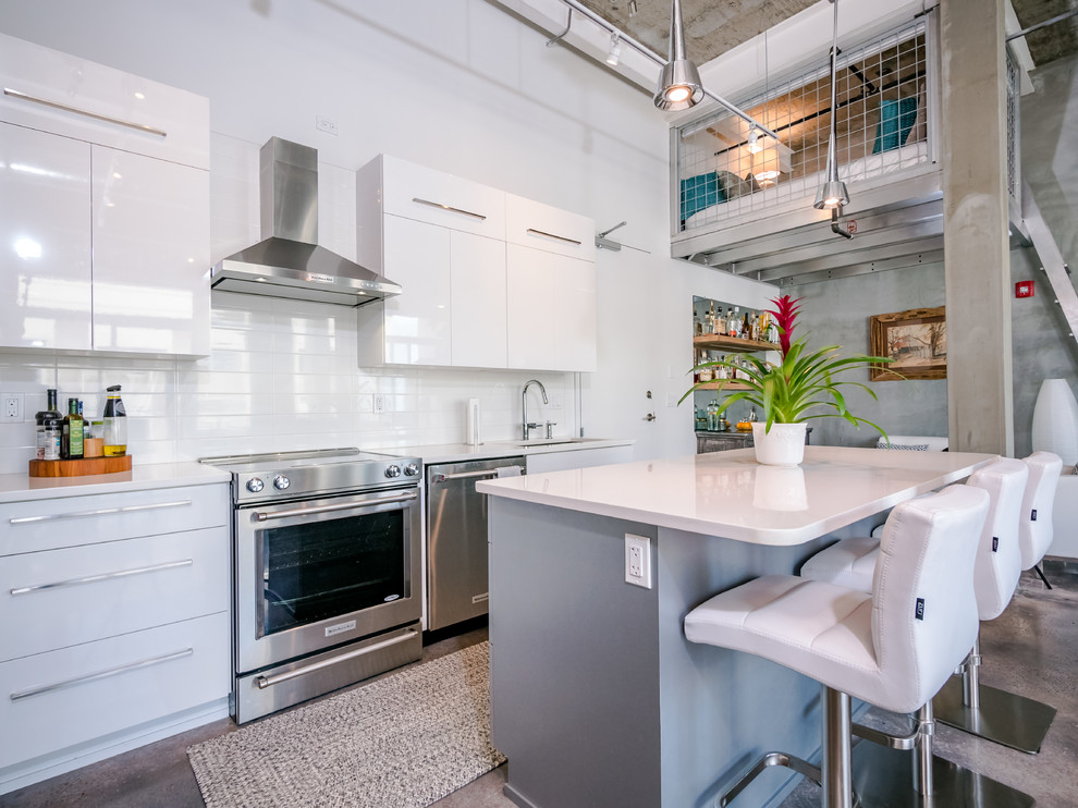 Foto di una cucina industriale con ante lisce, ante bianche, paraspruzzi bianco, elettrodomestici in acciaio inossidabile, pavimento in cemento, pavimento grigio e top bianco
