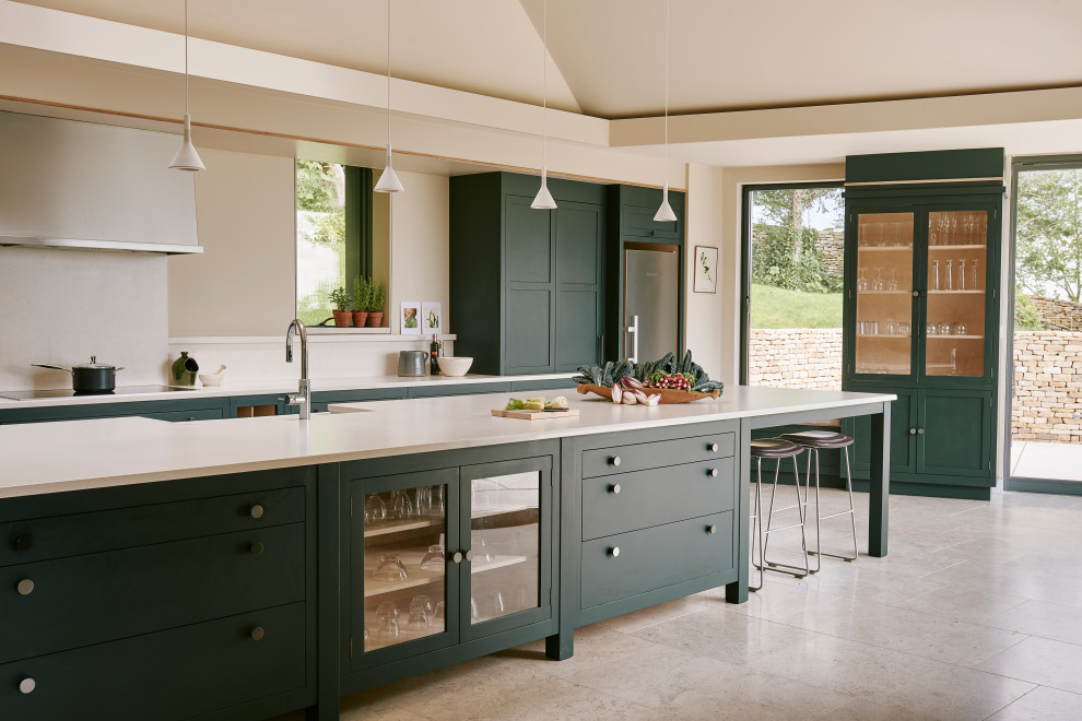 Photo of an expansive traditional open plan kitchen in Other with a belfast sink, shaker cabinets, green cabinets, composite countertops, stainless steel appliances, limestone flooring, an island and beige worktops.