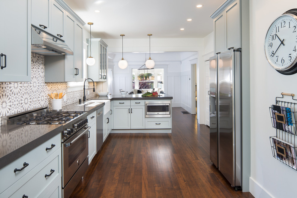 Inspiration for a contemporary u-shaped kitchen in San Francisco with a belfast sink, shaker cabinets, grey cabinets, composite countertops, grey splashback, cement tile splashback, stainless steel appliances and dark hardwood flooring.