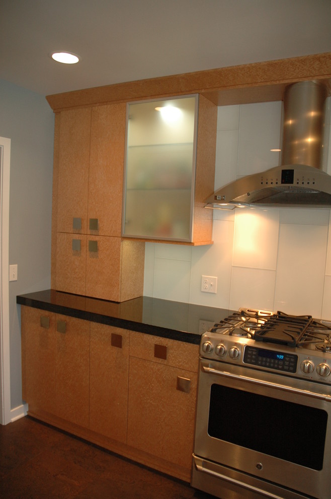 Foto på ett mellanstort funkis kök, med en undermonterad diskho, släta luckor, skåp i ljust trä, granitbänkskiva, vitt stänkskydd, stänkskydd i glaskakel, rostfria vitvaror och korkgolv