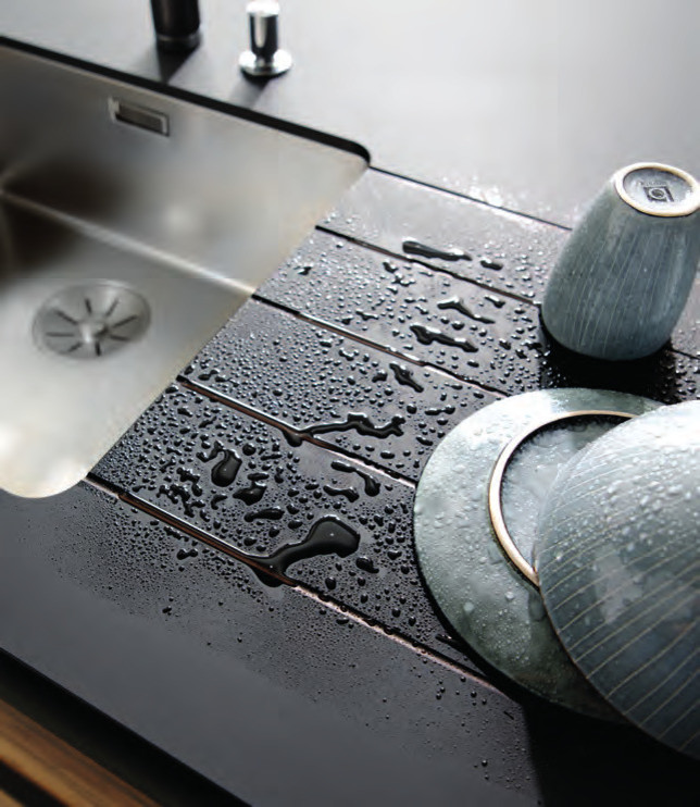 Foto di una cucina minimal di medie dimensioni con lavello a vasca singola, ante nere, top in quarzo composito, elettrodomestici neri, pavimento in cemento e pavimento grigio