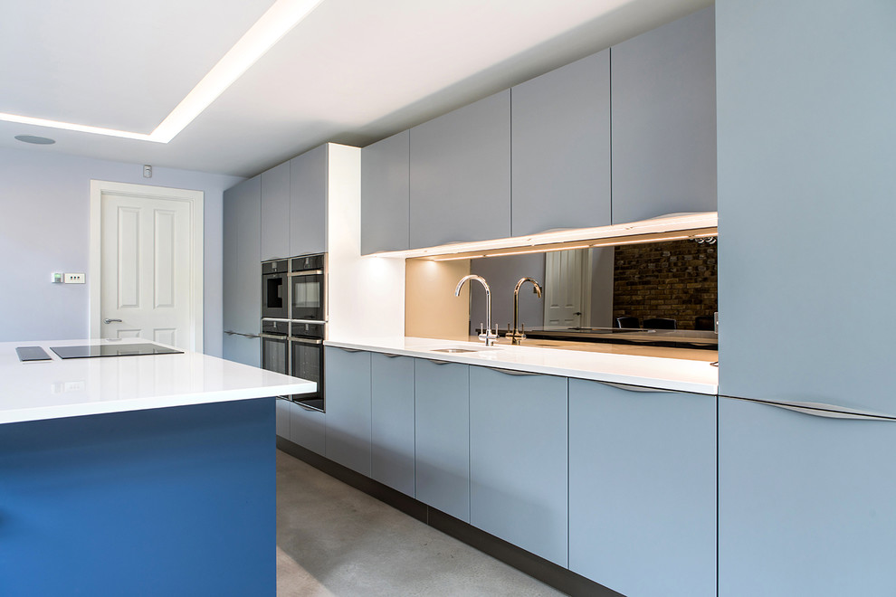 Bild på ett stort funkis linjärt kök och matrum, med en köksö, blå skåp, en enkel diskho, släta luckor, bänkskiva i kvartsit, spegel som stänkskydd och svarta vitvaror