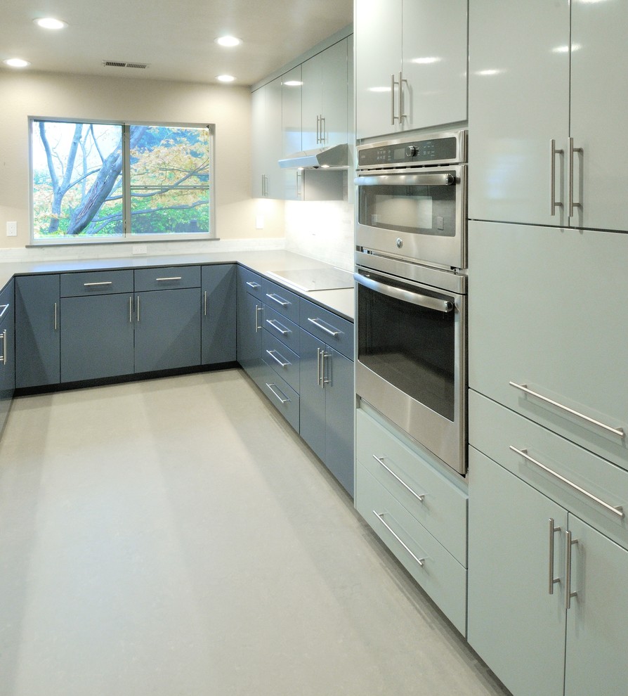 Inspiration for a mid-sized contemporary u-shaped linoleum floor enclosed kitchen remodel in Sacramento with an undermount sink, flat-panel cabinets, blue cabinets, solid surface countertops, gray backsplash, stone tile backsplash, stainless steel appliances and no island