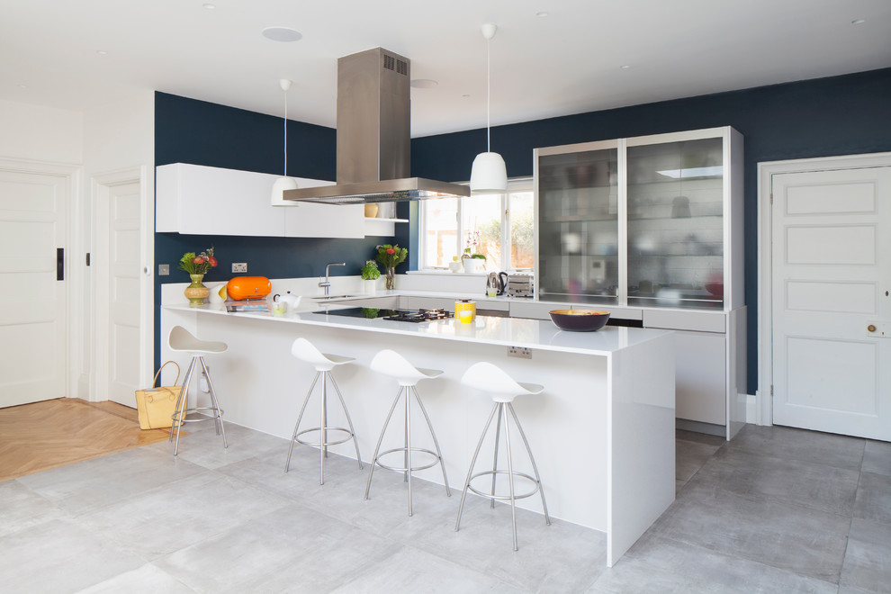 Cette image montre une cuisine design en U de taille moyenne avec un placard à porte vitrée, des portes de placard blanches, une péninsule et un sol gris.