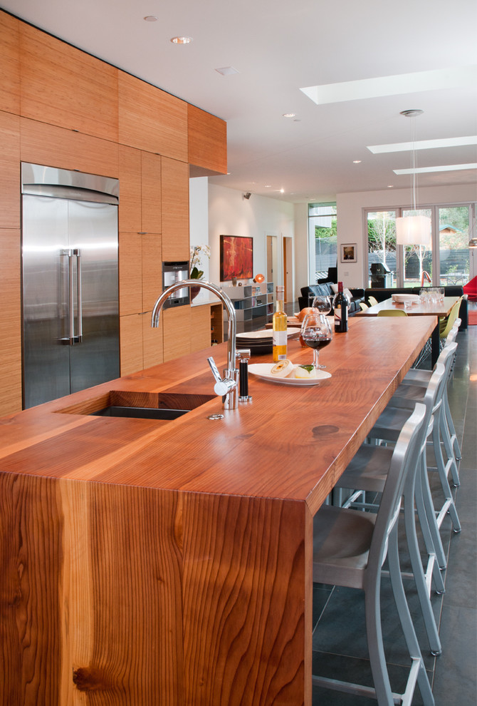 Example of a trendy galley open concept kitchen design in Vancouver with an undermount sink, flat-panel cabinets, medium tone wood cabinets, wood countertops and stainless steel appliances