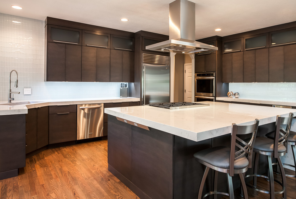 Foto på ett stort funkis kök, med en undermonterad diskho, släta luckor, skåp i mörkt trä, bänkskiva i kvarts, vitt stänkskydd, rostfria vitvaror, mellanmörkt trägolv och en köksö