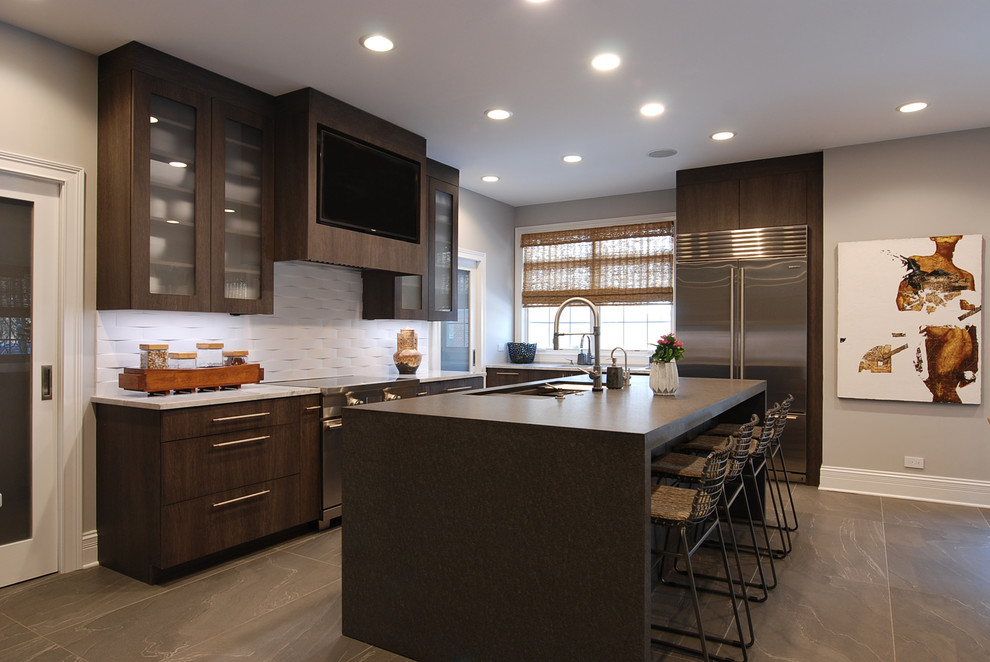 Photo of a medium sized contemporary l-shaped kitchen/diner in Chicago with a submerged sink, flat-panel cabinets, grey cabinets, quartz worktops, white splashback, porcelain splashback, stainless steel appliances, porcelain flooring, an island, grey floors and multicoloured worktops.