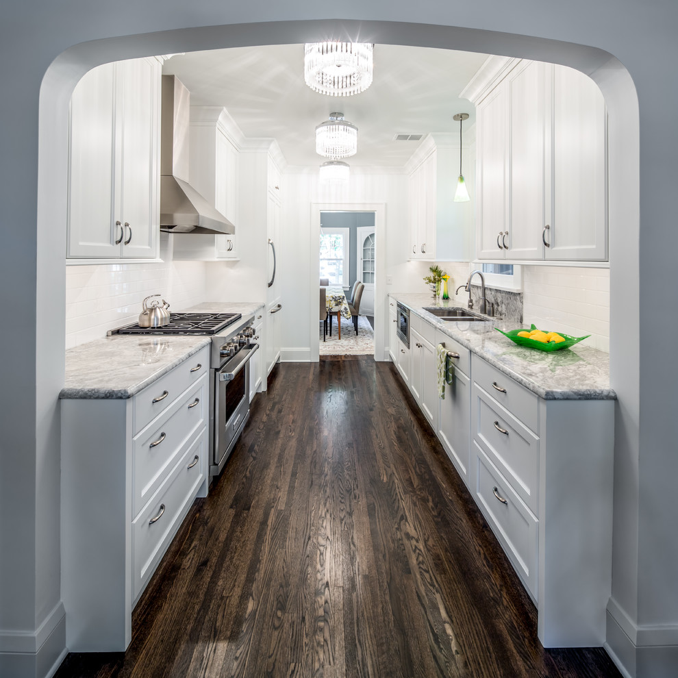 This is an example of a medium sized traditional galley enclosed kitchen in Minneapolis with a submerged sink, shaker cabinets, white splashback, white cabinets, granite worktops, metro tiled splashback, dark hardwood flooring, no island and brown floors.