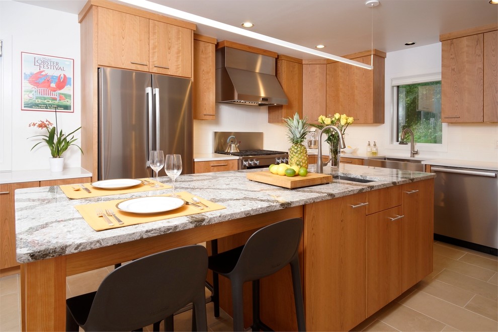 Inspiration for a medium sized contemporary galley enclosed kitchen in Philadelphia with a submerged sink, flat-panel cabinets, light wood cabinets, engineered stone countertops, white splashback, porcelain splashback, stainless steel appliances, porcelain flooring, an island, beige floors and white worktops.