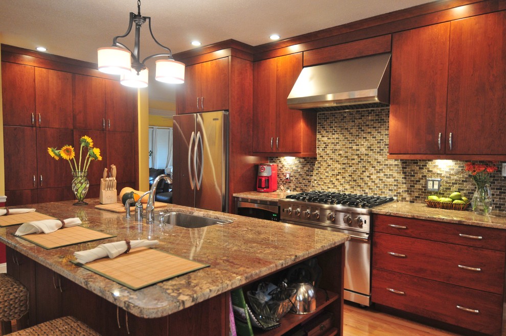 Exempel på ett klassiskt kök, med en undermonterad diskho, släta luckor, skåp i mellenmörkt trä, granitbänkskiva, flerfärgad stänkskydd, stänkskydd i mosaik, rostfria vitvaror, ljust trägolv och en köksö