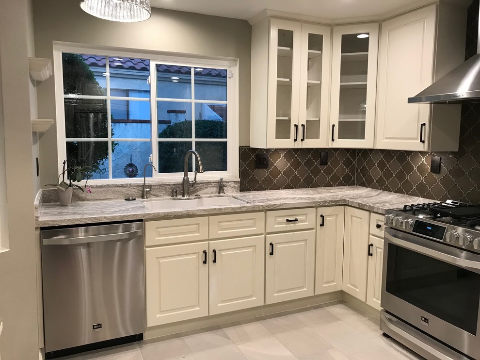 Eat-in kitchen - mid-sized contemporary u-shaped porcelain tile and white floor eat-in kitchen idea in Los Angeles with an undermount sink, raised-panel cabinets, white cabinets, quartz countertops, brown backsplash, glass tile backsplash, stainless steel appliances and no island